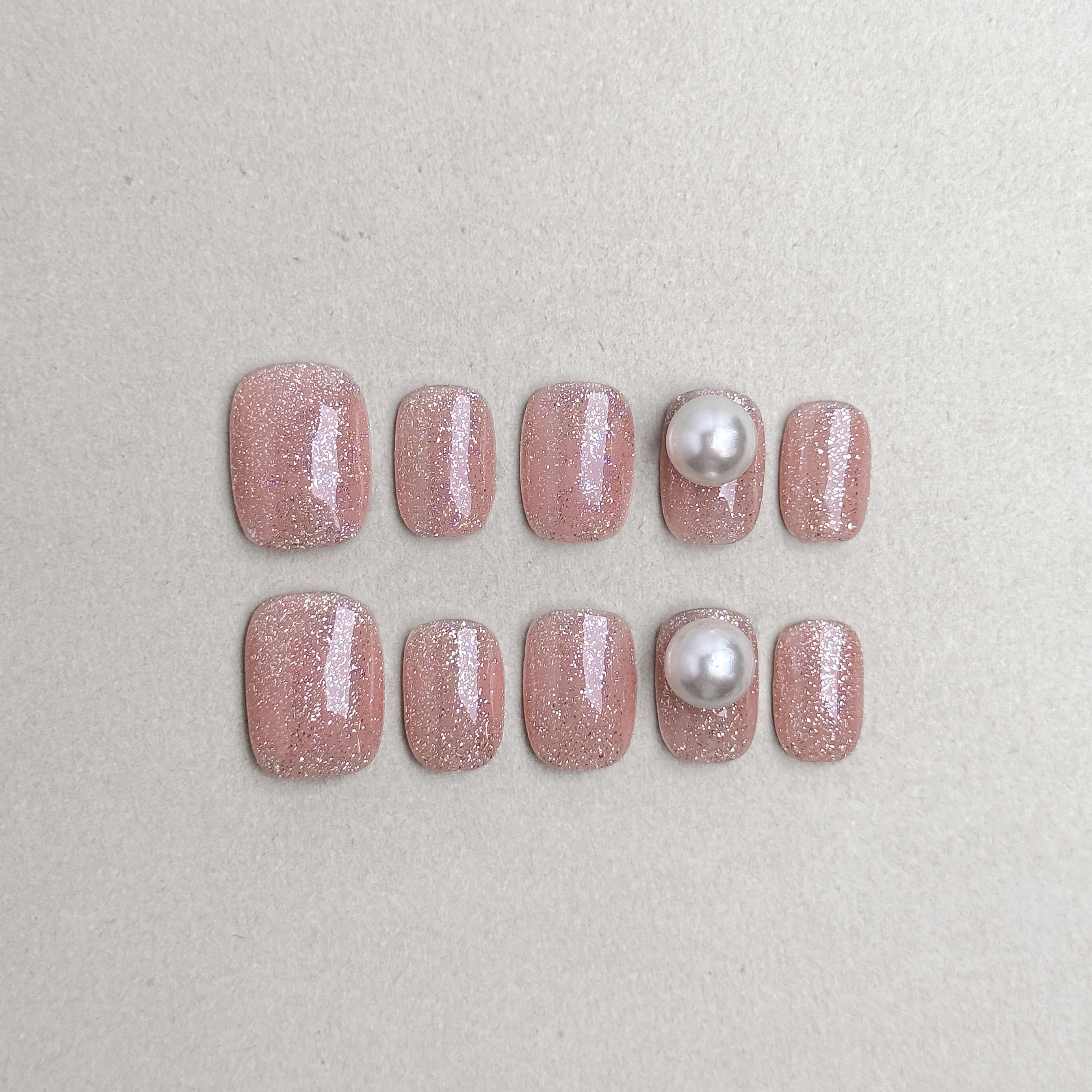 Set of reusable press-on nails in shimmering nude pink with pearl accents, MIBLAB Briller collection Geneva.