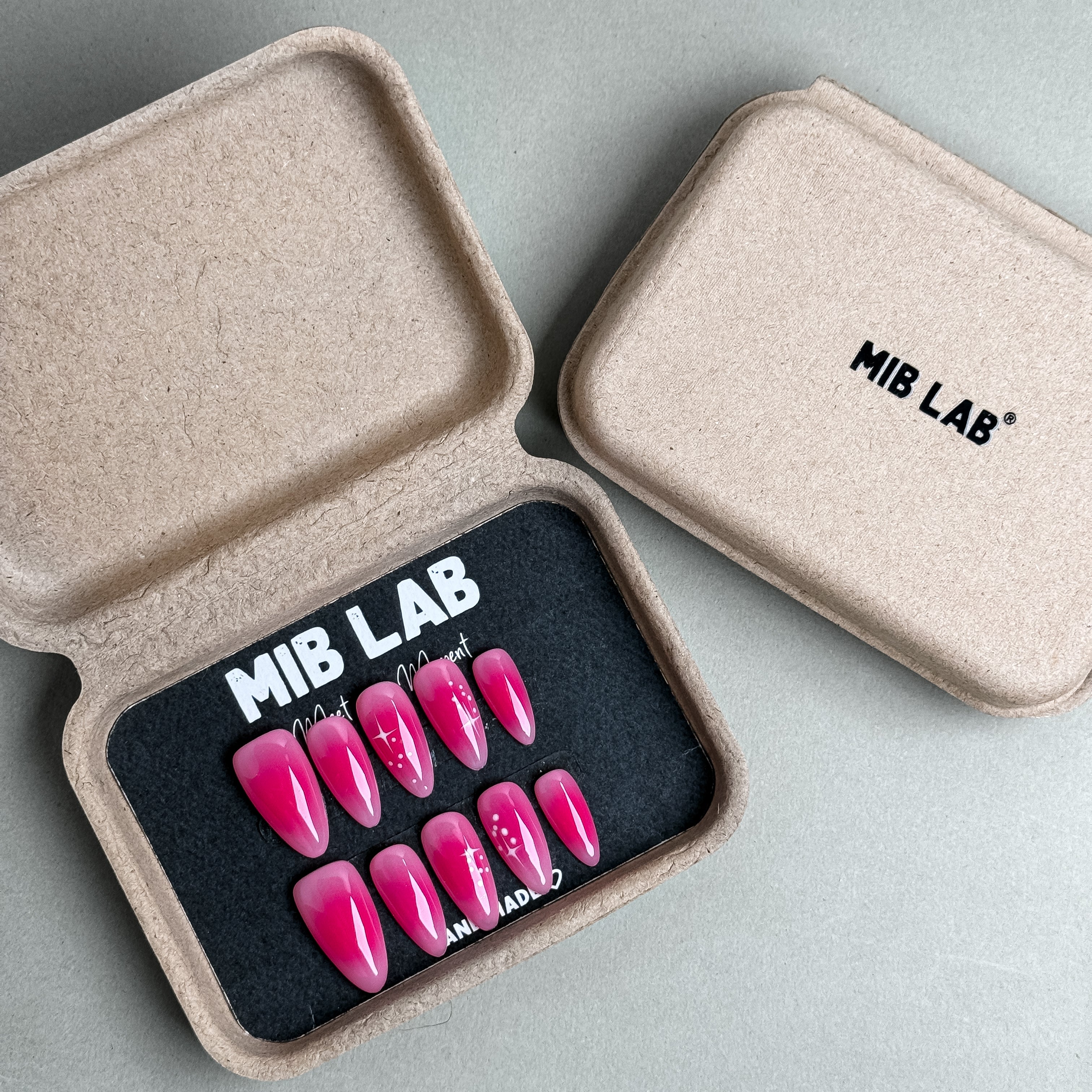 MIBLAB Cherry Bomb press-on nail set in bold fuchsia pink tone with high-shine surface, packaged for boutique display in Geneva.