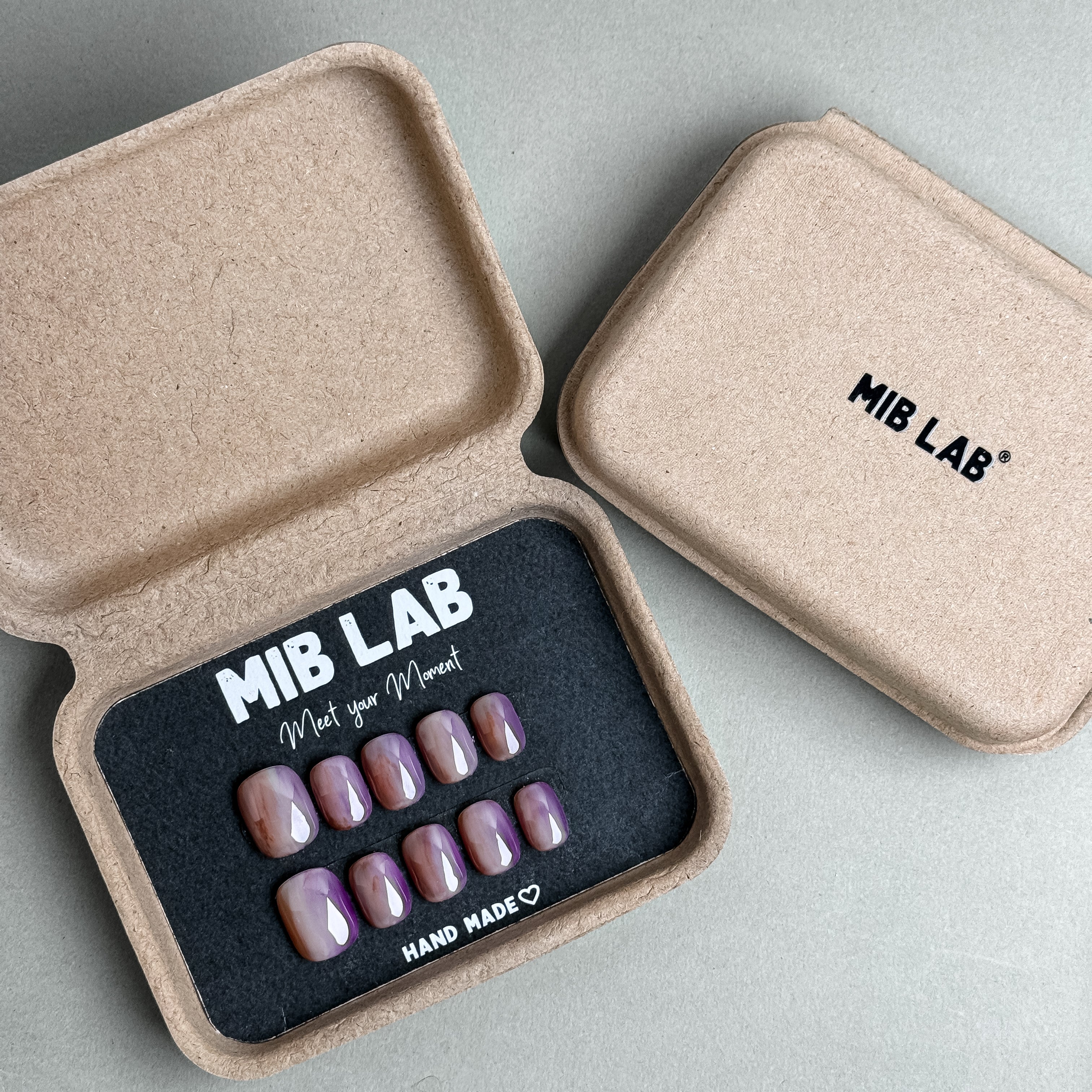 MIBLAB Emoi press-on nail set in soft mauve tone with high-shine surface, packaged for boutique display in Geneva.