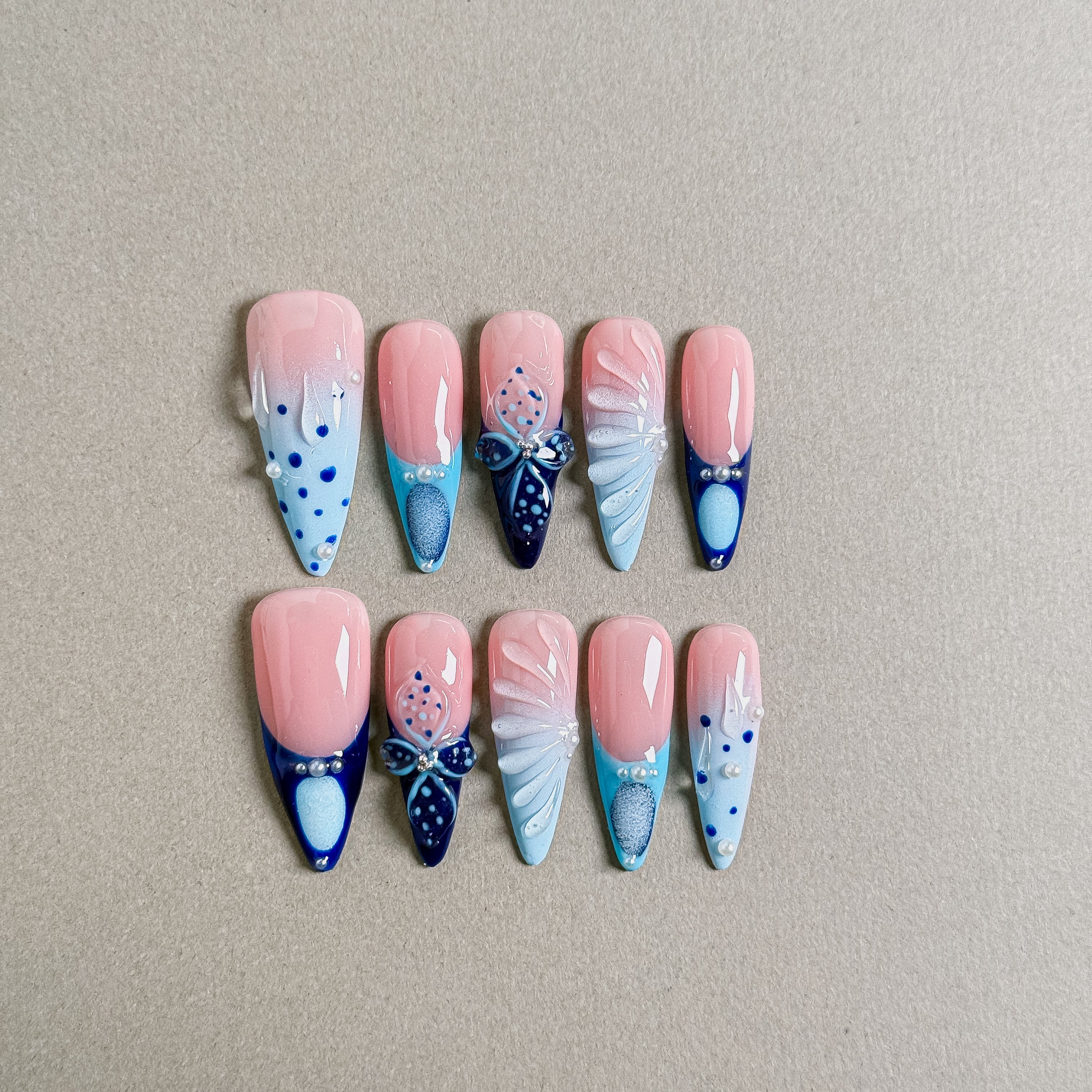 A set of "Tide" stiletto - shaped press - on nails in soft pink, blue, and navy hues, adorned with nautical - inspired designs like bows, dots, and frosty patterns, ideal for adding a maritime - themed charm to party nail looks.
