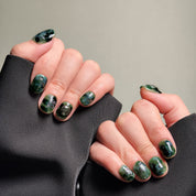 Short nails design showcasing a deep green, iridescent pattern, creating a captivating and unique look. These Custom press on nails are perfect for adding a touch of bold elegance to any outfit. The intricate details and rich color make them ideal for Party nails or special occasions.  These Handmade press on nails demonstrate expert craftsmanship and are perfect for those seeking Luxury press on nails that stand out.