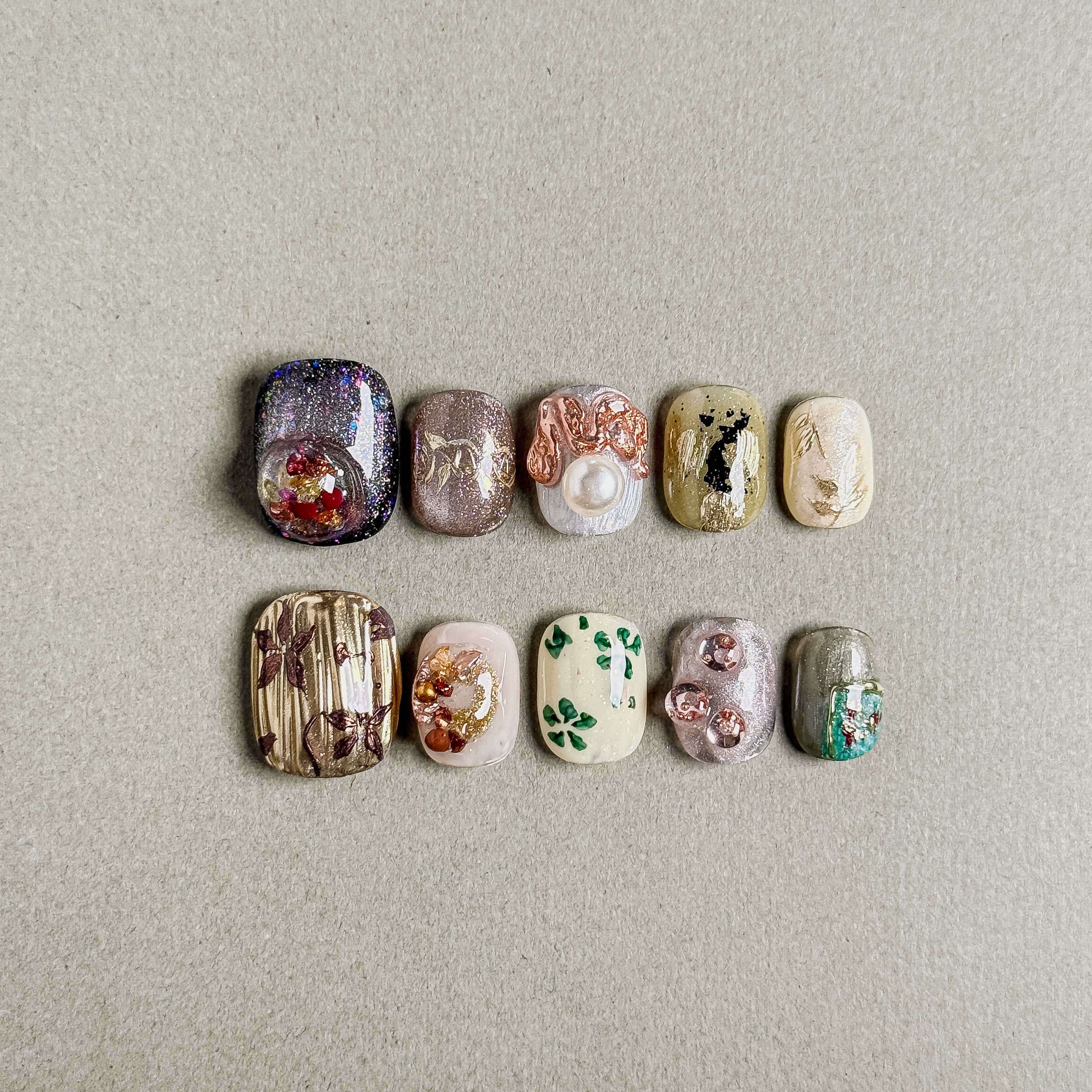 A set of "Florentine" press - on nails with intricate designs including glitter, pearls, floral motifs, and metallic accents, ideal for creating an opulent and unique nail style for weddings.
