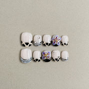 A set of "Wild Summer" press - on nails with a mix of white bases adorned with black patterns, delicate flowers, and small rhinestones, ideal for adding a lively touch to holiday party nail looks.
