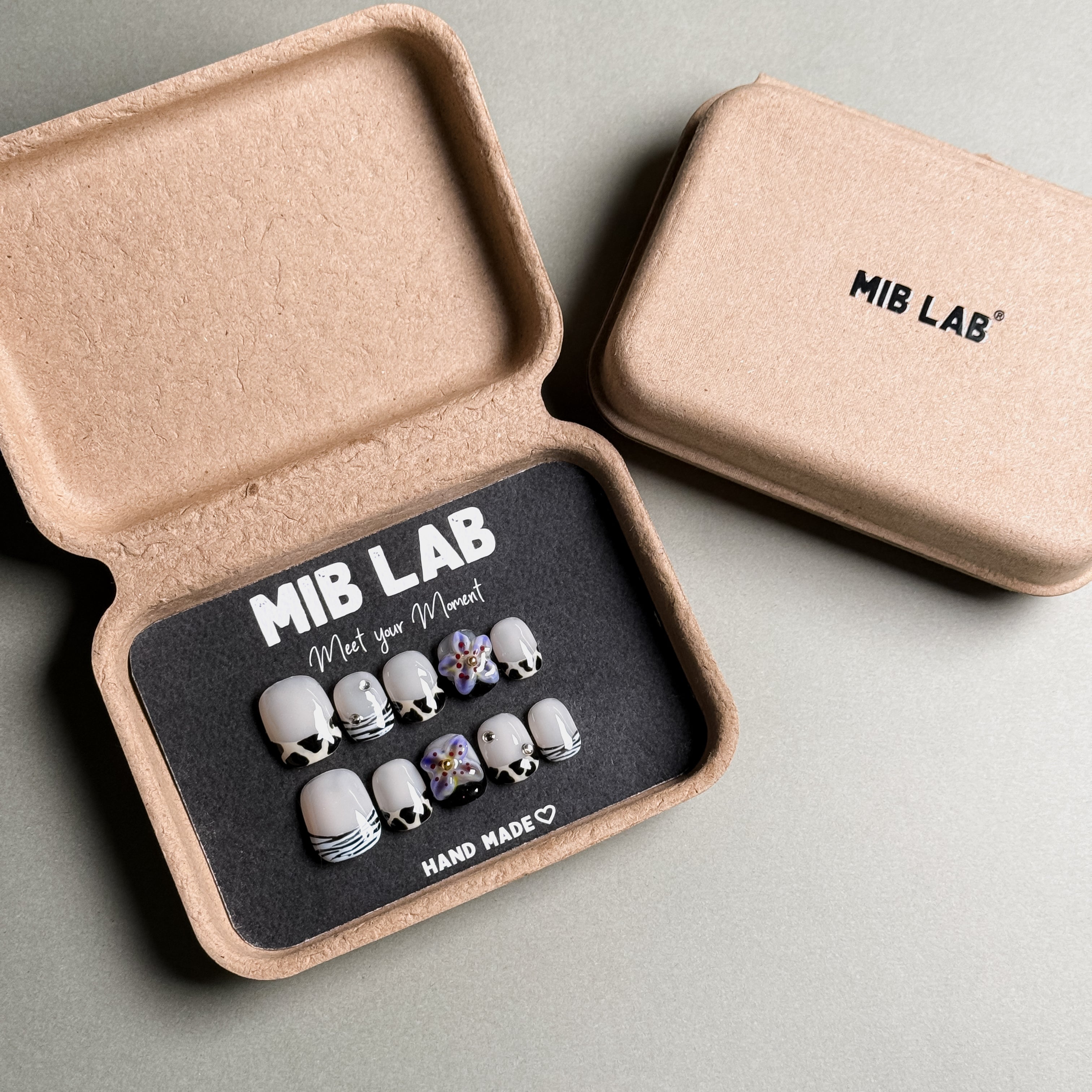 A set of custom press on nails from MIBLAB featuring a unique nail art design with floral and striped patterns. These handmade press on nails are presented in their eco-friendly packaging, highlighting the attention to detail. This set offers a creative and stylish short nails design, perfect for adding a personal touch to your look.