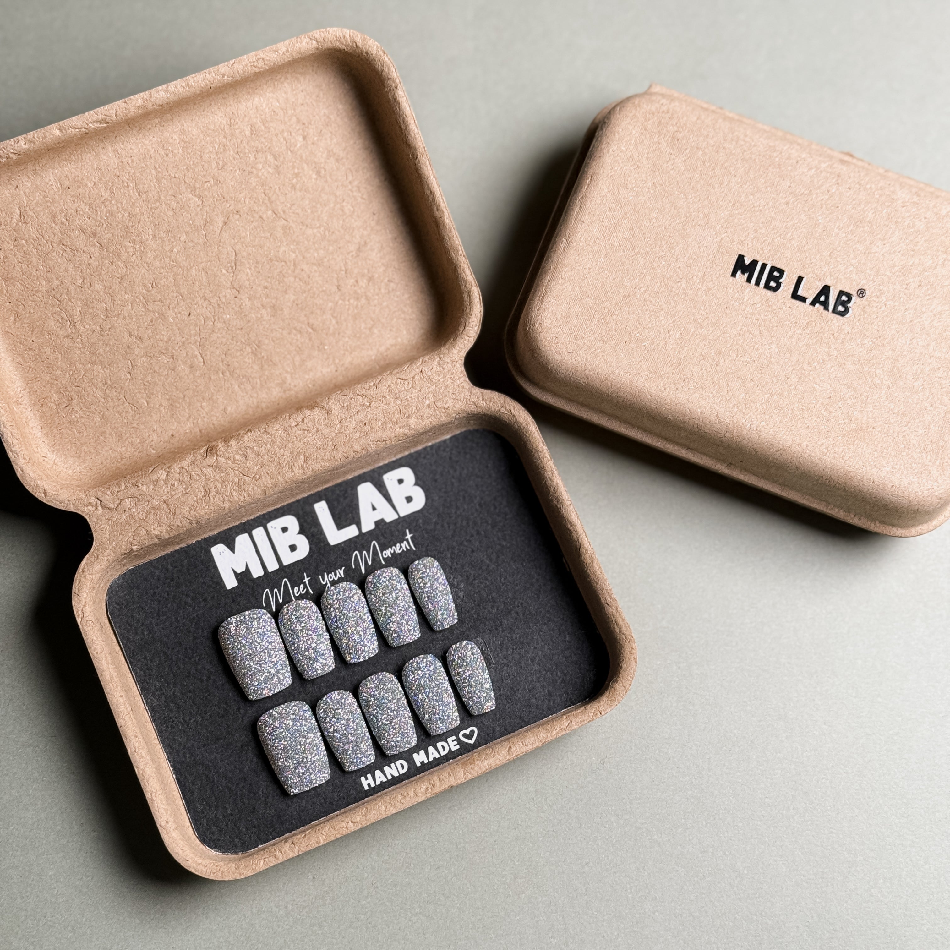 A set of beautiful, glittery luxury press on nails presented in their packaging from MIBLAB. These appear to be handmade press on nails, as indicated on the packaging. This showcases a set of fake nails ready to be applied for an instant manicure. Perfect for those looking for convenient and stylish nail enhancements.