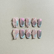 A set of "Aqua" press - on nails with a soft pink base, adorned with iridescent glitter, intricate designs, and small pearl accents, perfect for adding a touch of elegance to wedding or party nail looks.