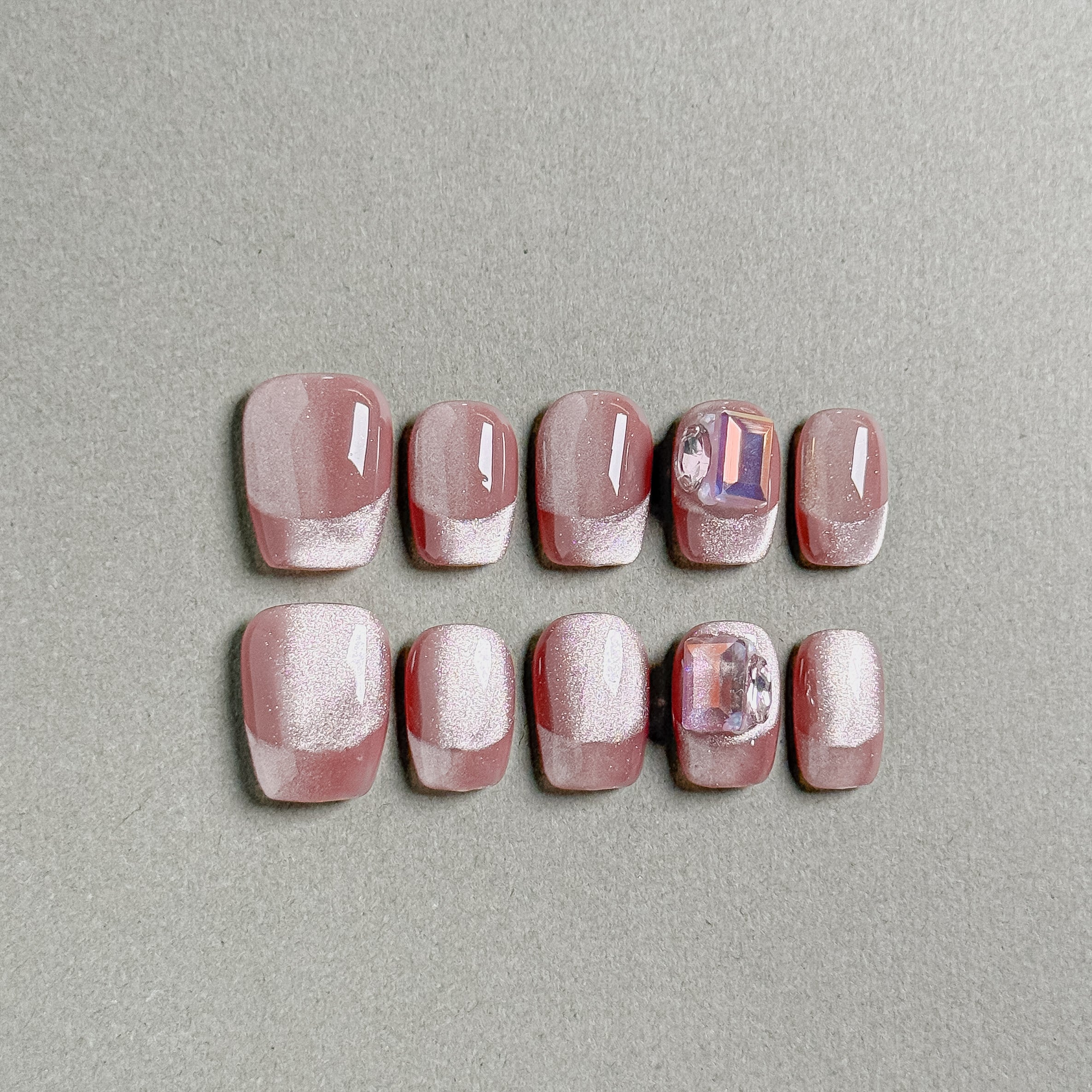 A set of "Carats" press - on nails in a rosy hue, adorned with glitter and featuring some nails with gem - like embellishments, perfect for adding a touch of luxury to party nail art.