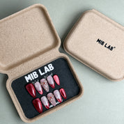 MIBLAB Last Christmas press-on nail set in festive red and nude tones with sparkling gold details, packaged for boutique display in Geneva.