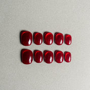 A set of "Echo" red glittery press - on nails with a glossy finish, arranged in two rows for a complete nail set, suitable for festive holiday nail art designs.