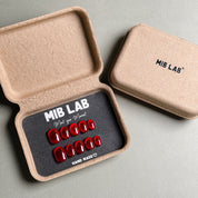 MIBLAB brand red press-on nails set featuring a high-gloss finish, packaged in an eco-friendly recycled paper box with the brand name "MIB LAB" and the slogan "Meet your Moment" displayed, along with the "HAND MADE ♡" inscription, presented against a neutral gray background, showcasing short nails design. These fake nails offer a quick and easy solution for achieving a bold and glamorous look, suitable for party nails or holiday nails.