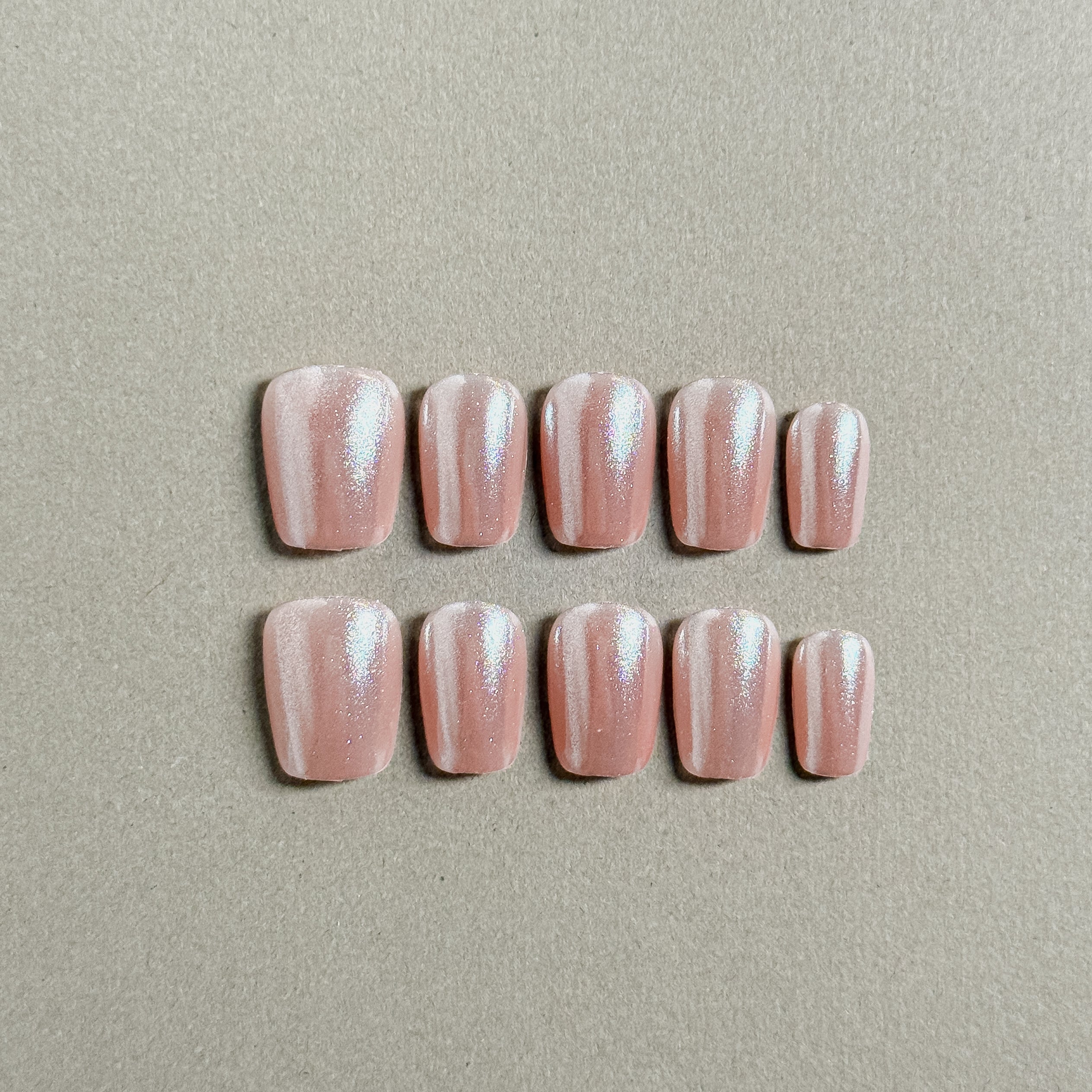 A set of Blush - named glittery custom press - on nails with a soft pink hue and shimmering glitter stripes, ideal for party and wedding nail art styles.