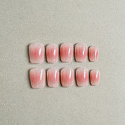 Two rows of MIBLAB's pink press-on nails featuring a delicate French tip nails design with a soft pink gradient effect, arranged against a neutral gray background to highlight the subtle color transition and elegant style, with a gradient of sizes from large to small for a perfect fit, showcasing short nails design. These fake nails offer a quick and easy solution for achieving a natural looking nails effect, suitable for everyday nails or as wedding nails.