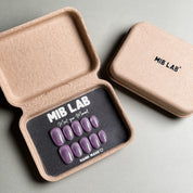 A set of Handmade press on nails with a solid purple color, presented in eco-friendly packaging. These Minimalist nails offer a clean and sophisticated look, perfect for Everyday nails and professional settings. The box, labeled "MIB LAB" and "Meet Your Moment", highlights the brand's dedication to creating timeless Nail art designs. Ideal for those seeking Reusable fake nails that are both stylish and sustainable.