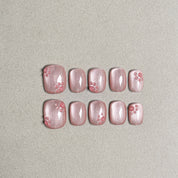 Two rows of MIBLAB's light pink press-on toenails with delicate pink floral designs, featuring a subtle shimmer and a glossy finish, arranged against a neutral gray background to highlight the intricate details and soft color palette, with a gradient of sizes from large to small for a perfect fit.
