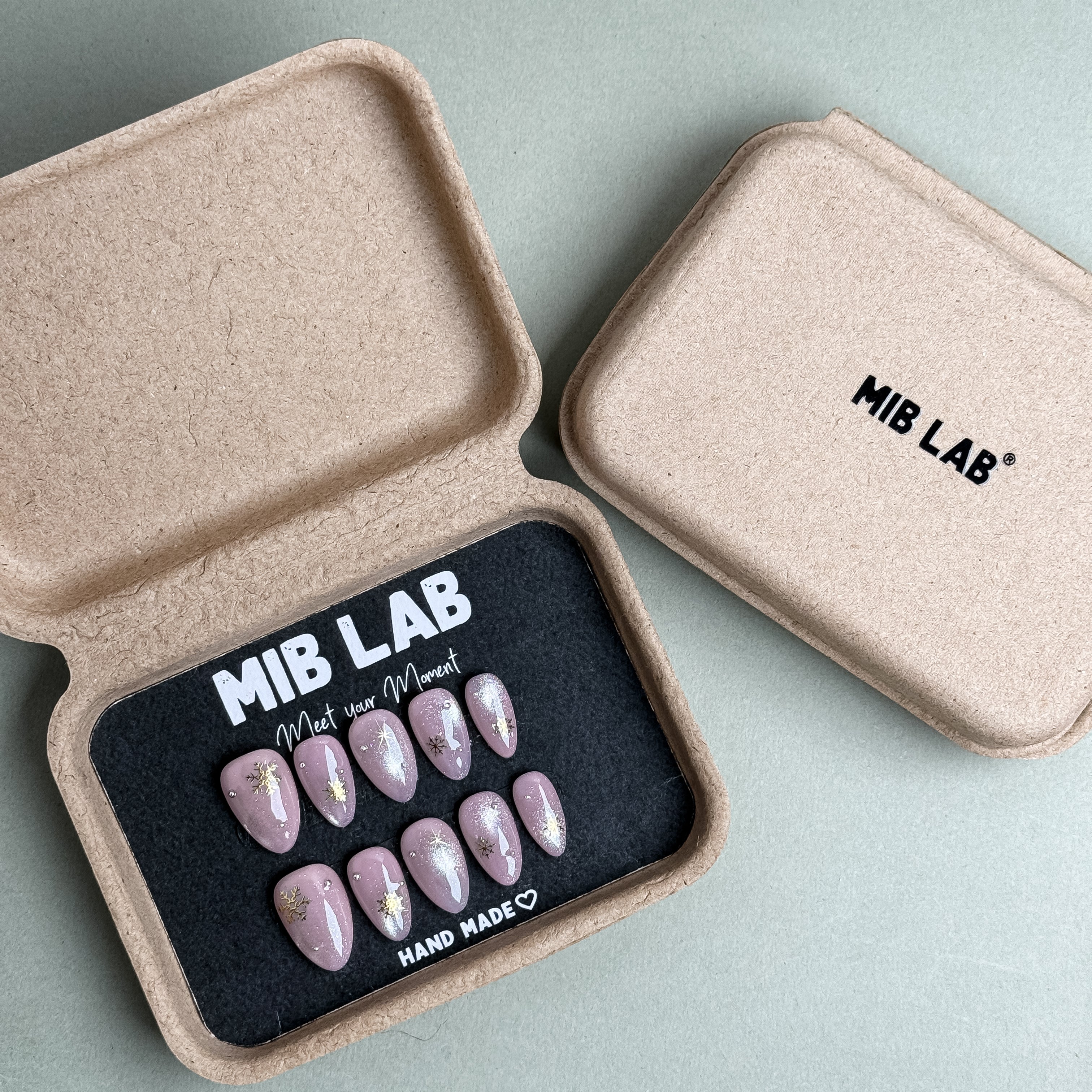 MIBLAB PinkMas press-on nail set in pastel pink with metallic gold details, packaged for boutique display in Geneva.