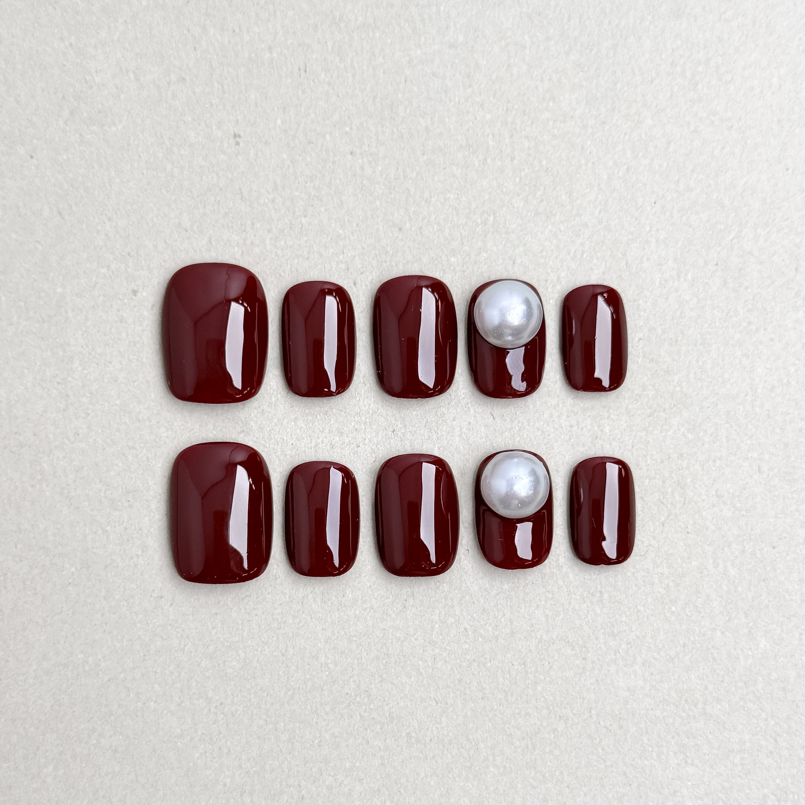 Set of reusable press-on nails in deep wine red with pearl accents, MIBLAB Sip Me collection Geneva.