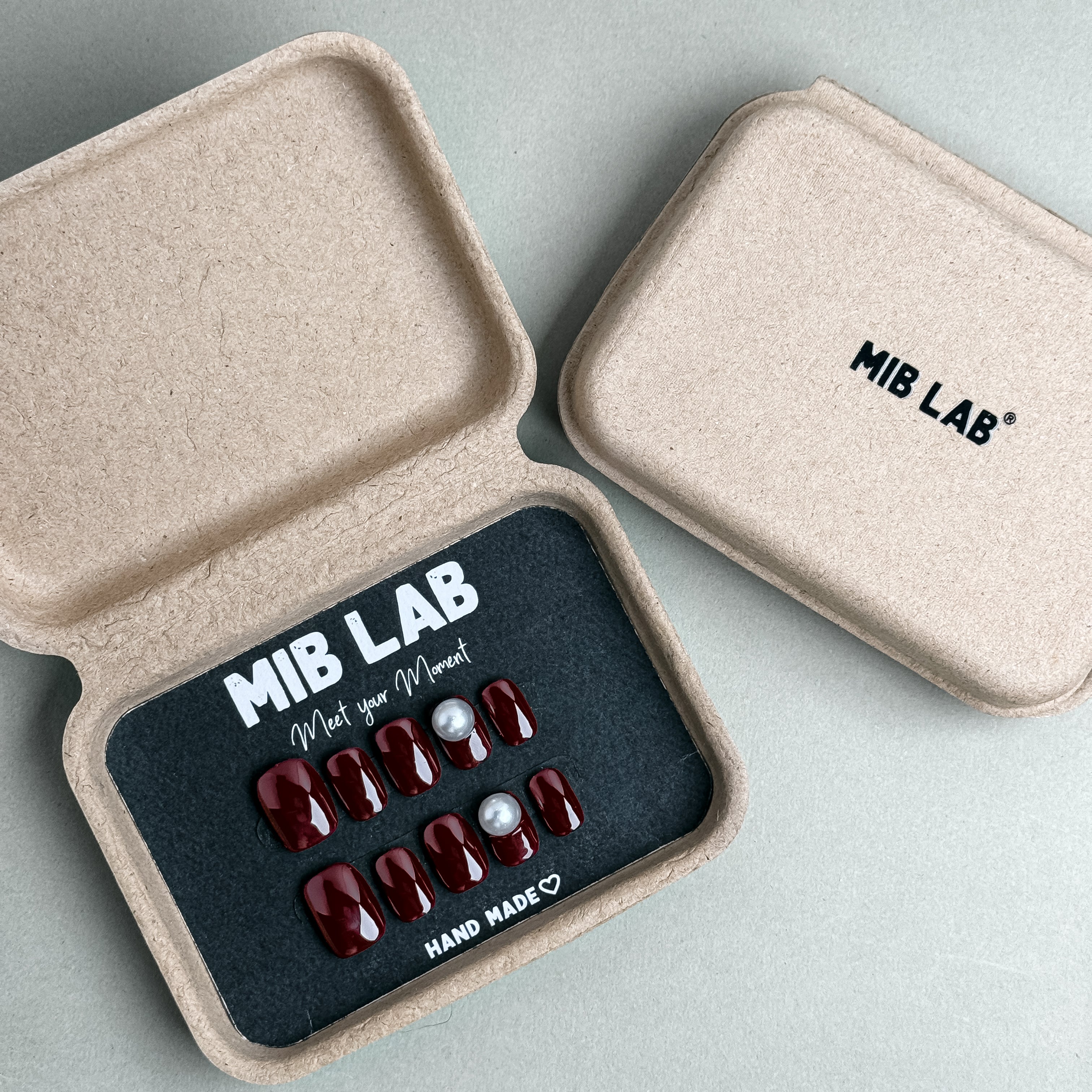 MIBLAB Sip Me press-on nail set in rich burgundy tone with glossy finish and pearl details, packaged for boutique display in Geneva.