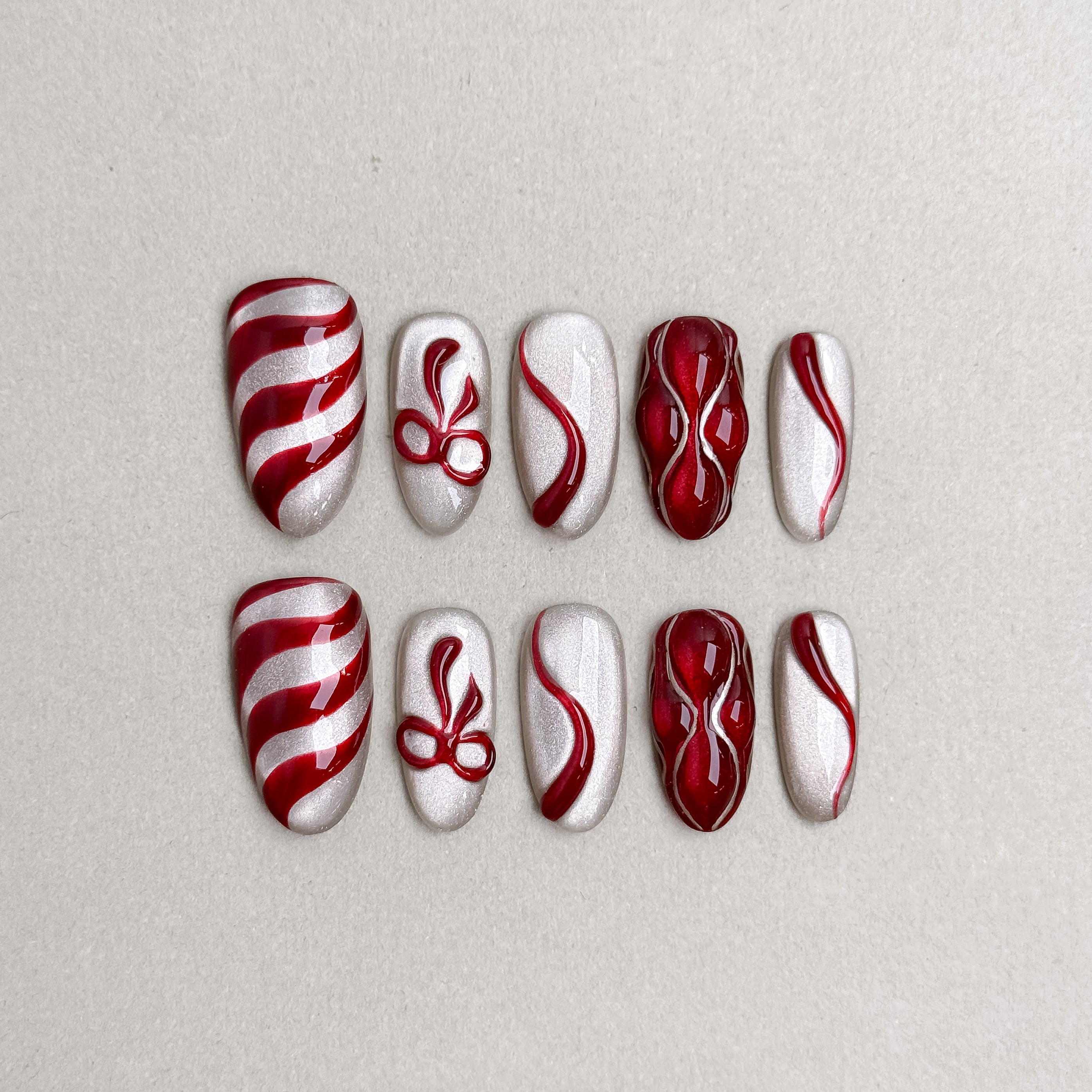 Set of reusable press-on nails in candy cane red and white swirl design, MIBLAB Wrap Me Up collection Geneva.