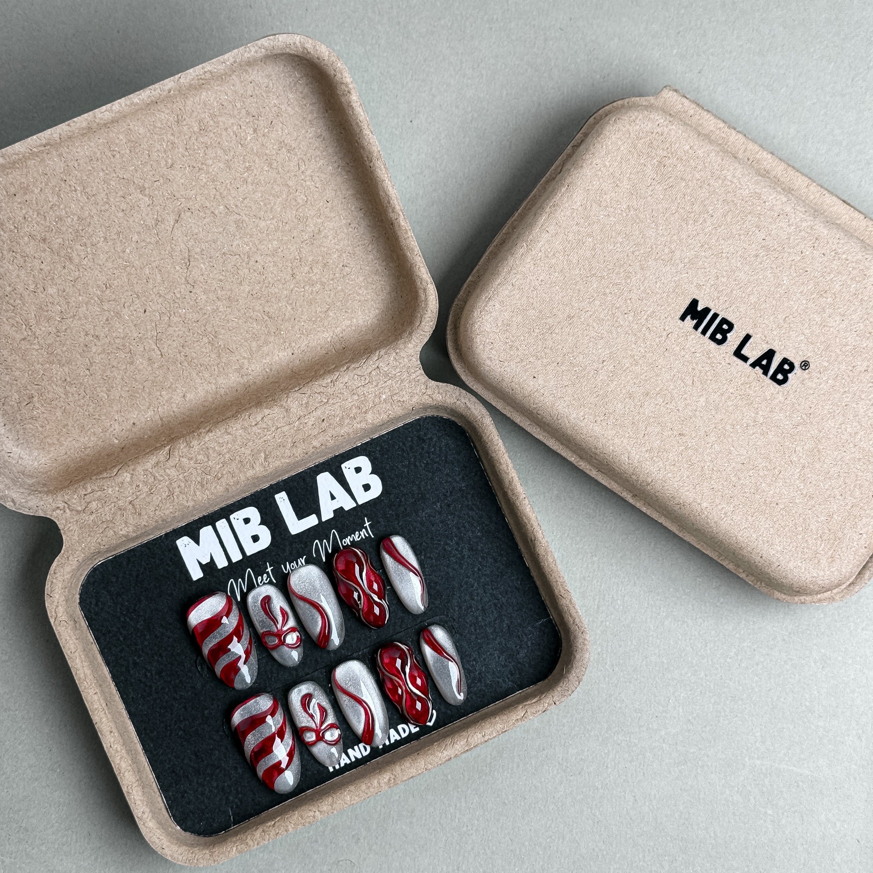 MIBLAB Wrap Me Up press-on nail set featuring festive red and white ribbon patterns, packaged for boutique display in Geneva.