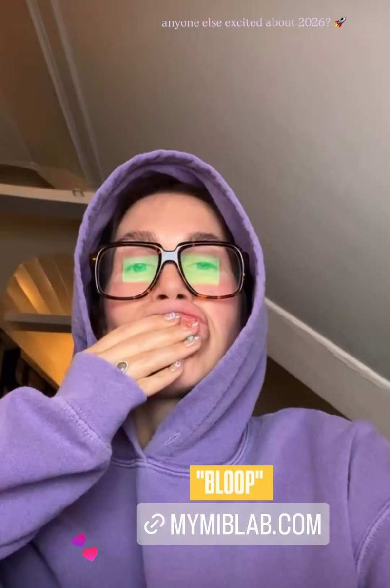 Selfie en hoodie violet et grandes lunettes : la personne couvre sa bouche avec la main pour montrer une manucure press-on ; texte “BLOOP” et MYMIBLAB.COM.