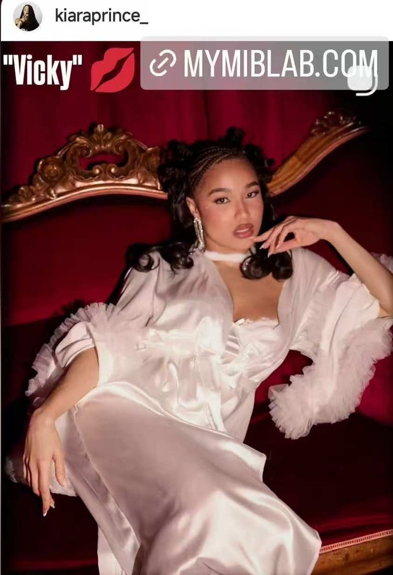 Photo style éditorial : une femme en robe satinée blanche est allongée sur un canapé rouge, mettant en valeur ses press-on nails ; mention “Vicky” et MYMIBLAB.COM.