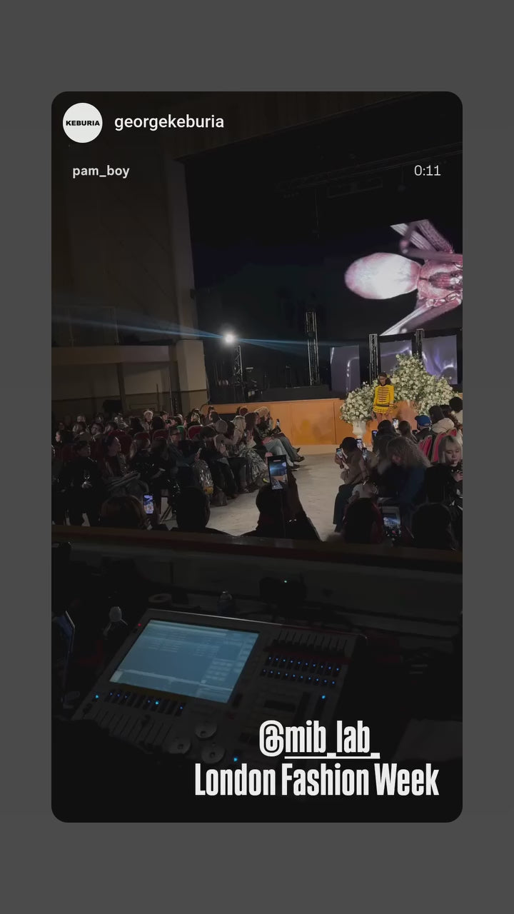 Défilé London Fashion Week : vue sur le runway depuis la régie/console, un mannequin en tenue jaune défile devant le public ; tag @mib_lab.