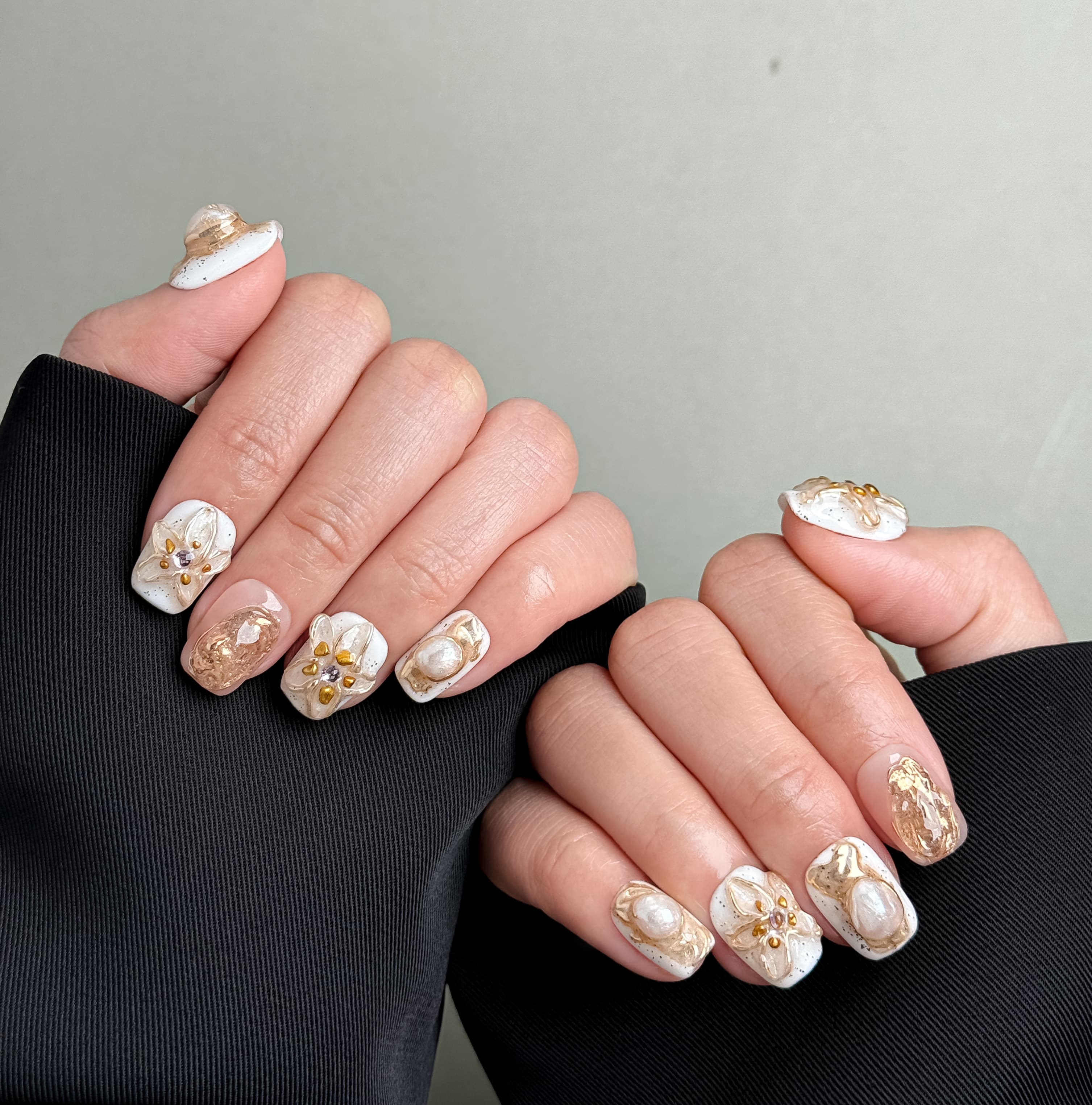 Manucure Stillness portée : press on nails nude avec fleurs blanches, look doux et élégant, ongles sans gel, Genève.