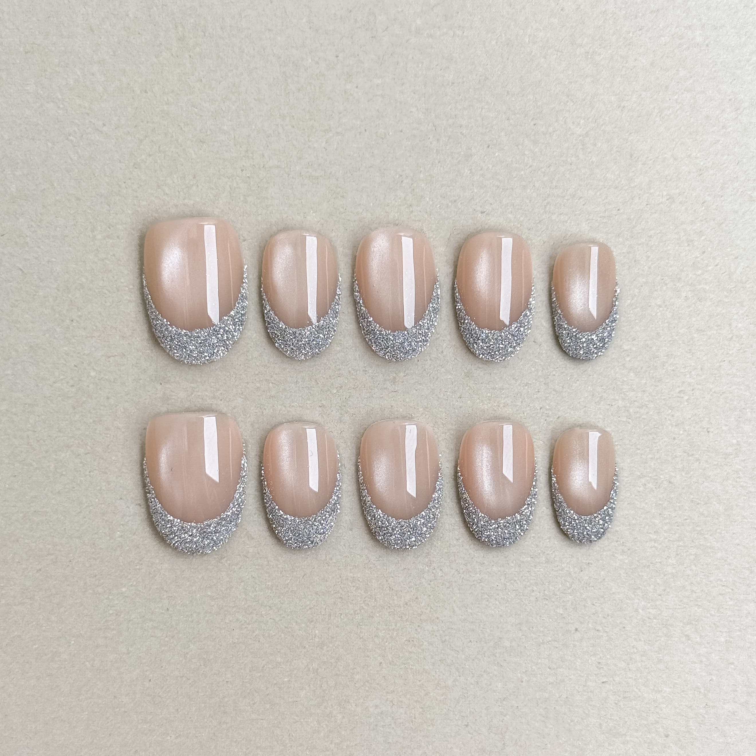Éveil : faux ongles réutilisables nude rosé, reflets nacrés et bord argenté pailleté, press on nails premium, finition brillante.