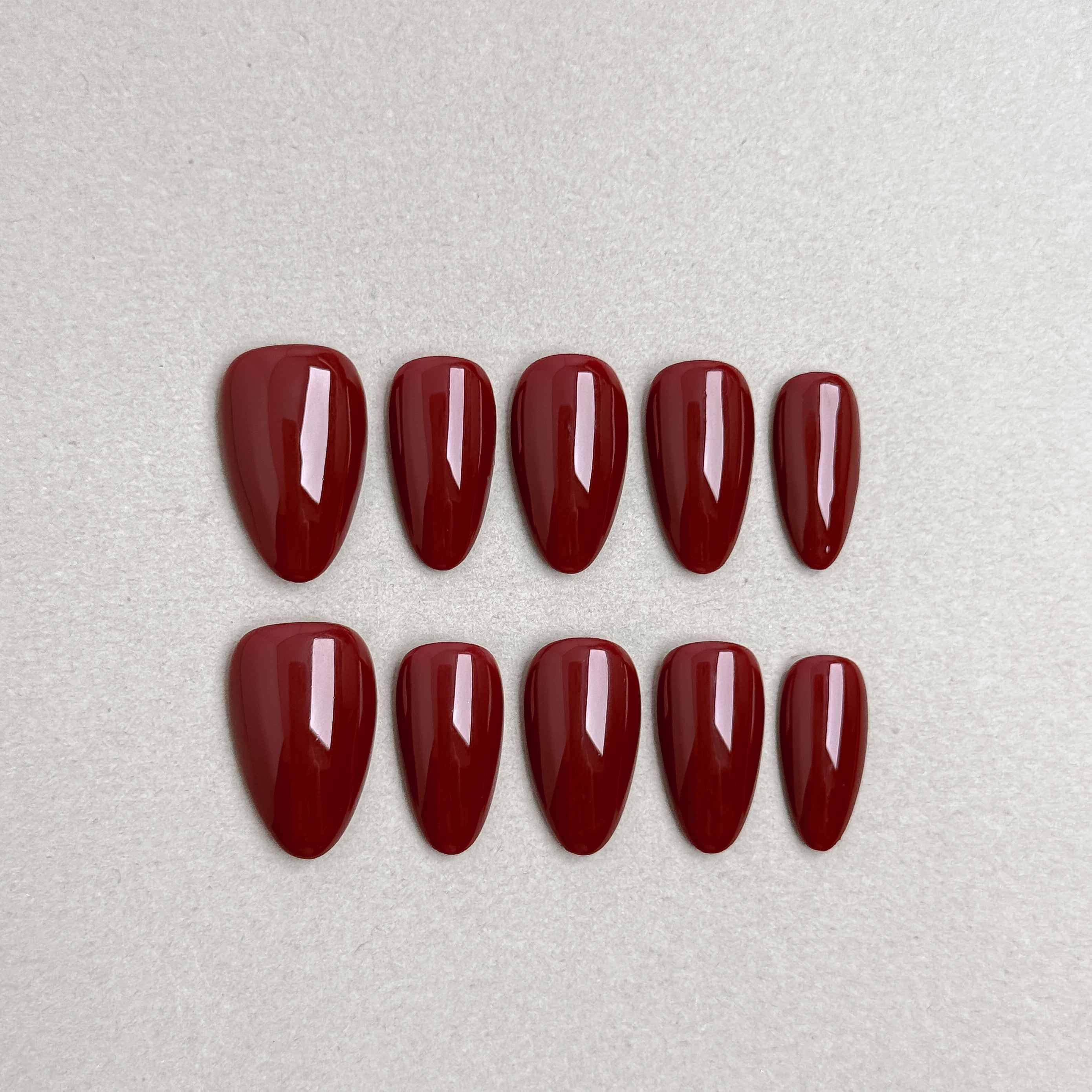 Set of reusable press-on nails in deep wine red with glossy finish, MIBLAB Wine Not Almond collection Geneva.