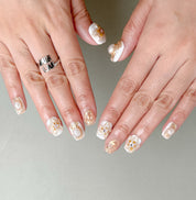 Stillness sur mains : faux ongles réutilisables nude, design floral minimal chic, manucure rapide, Genève et Suisse.