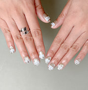 Gros plan The Light : faux ongles réutilisables nude translucide, détails blancs en relief, tenue longue durée, Suisse.