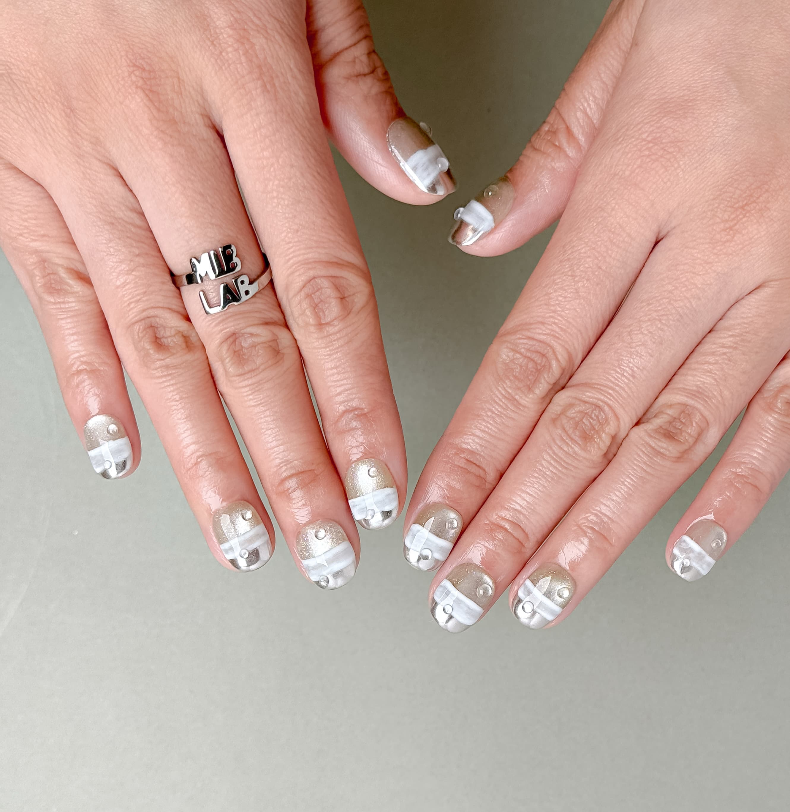 Gros plan The Light : faux ongles réutilisables nude translucide, détails blancs en relief, tenue longue durée, Suisse.