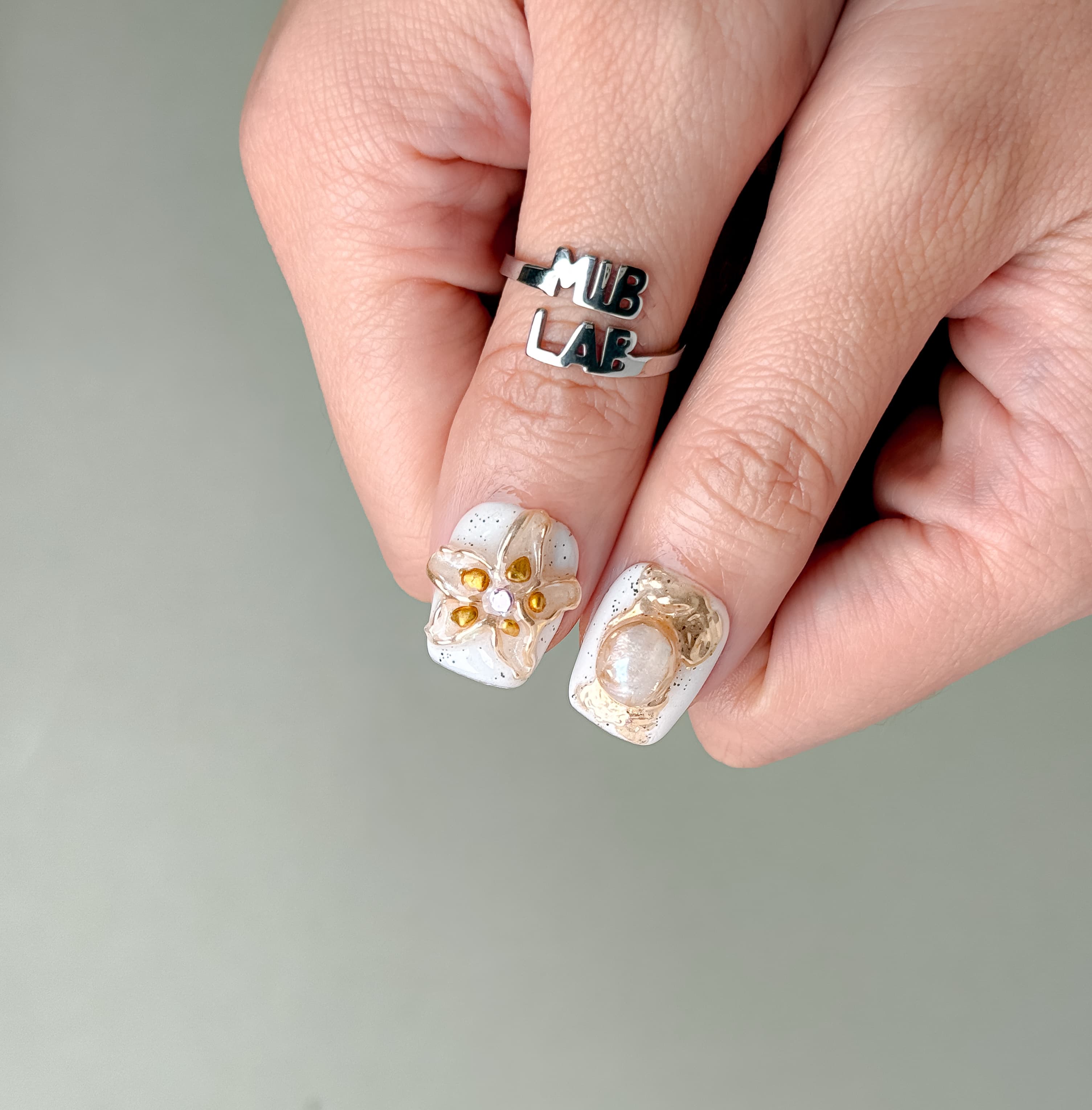 Gros plan Stillness : press on nails premium réutilisables fleurs blanches en relief, fini glossy, tenue longue durée, Suisse.