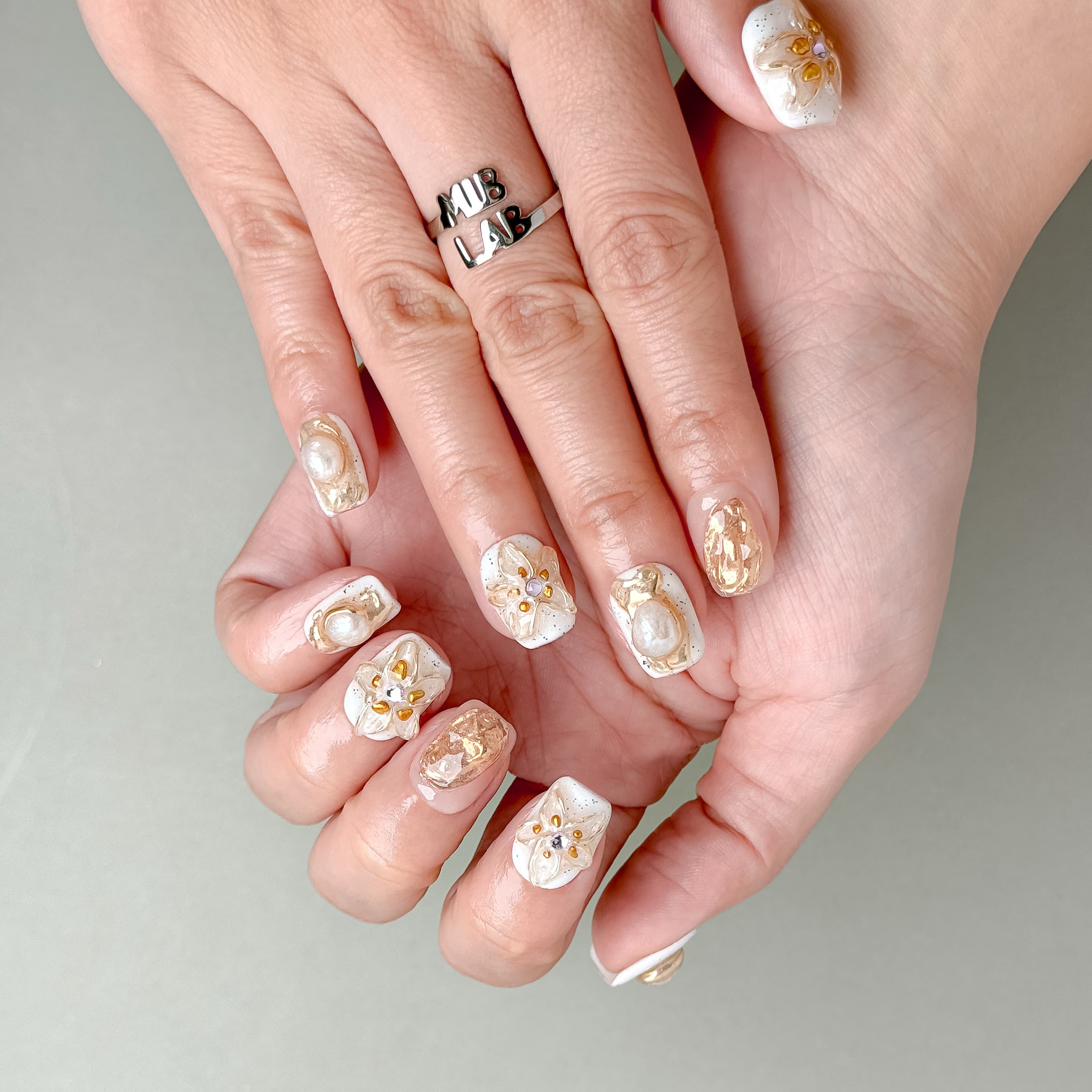 Détail Stillness sur mains : faux ongles premium réutilisables avec accents dorés, style mariage ou événement, Suisse.