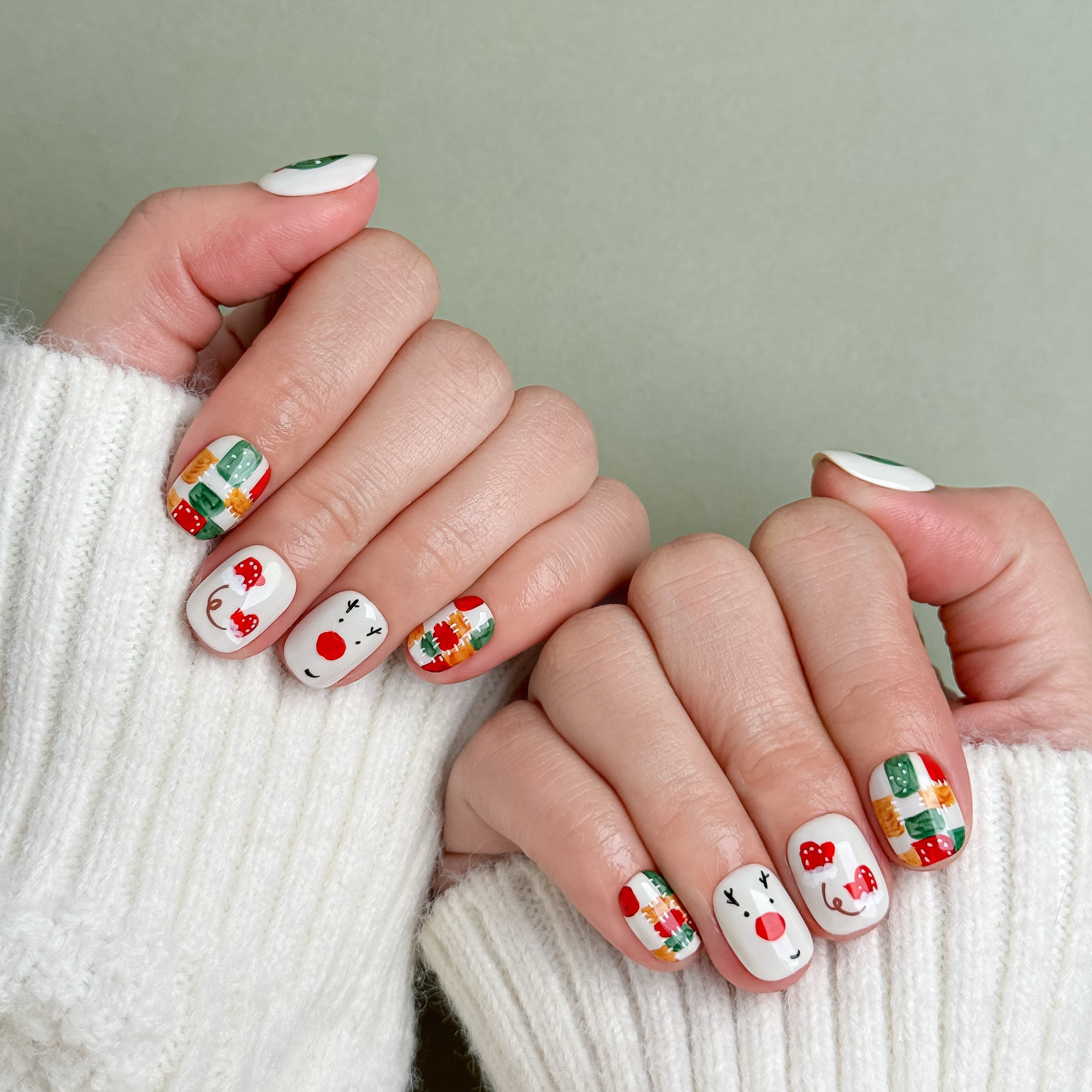 Model wearing MIBLAB Let It Snow Christmas-themed press-on nails with snowman and wreath designs, handcrafted reusable design available in Geneva.