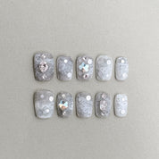 Instinct : faux ongles réutilisables gris perlé, reflets nacrés et touches bijoux, press on nails premium, finition brillante.