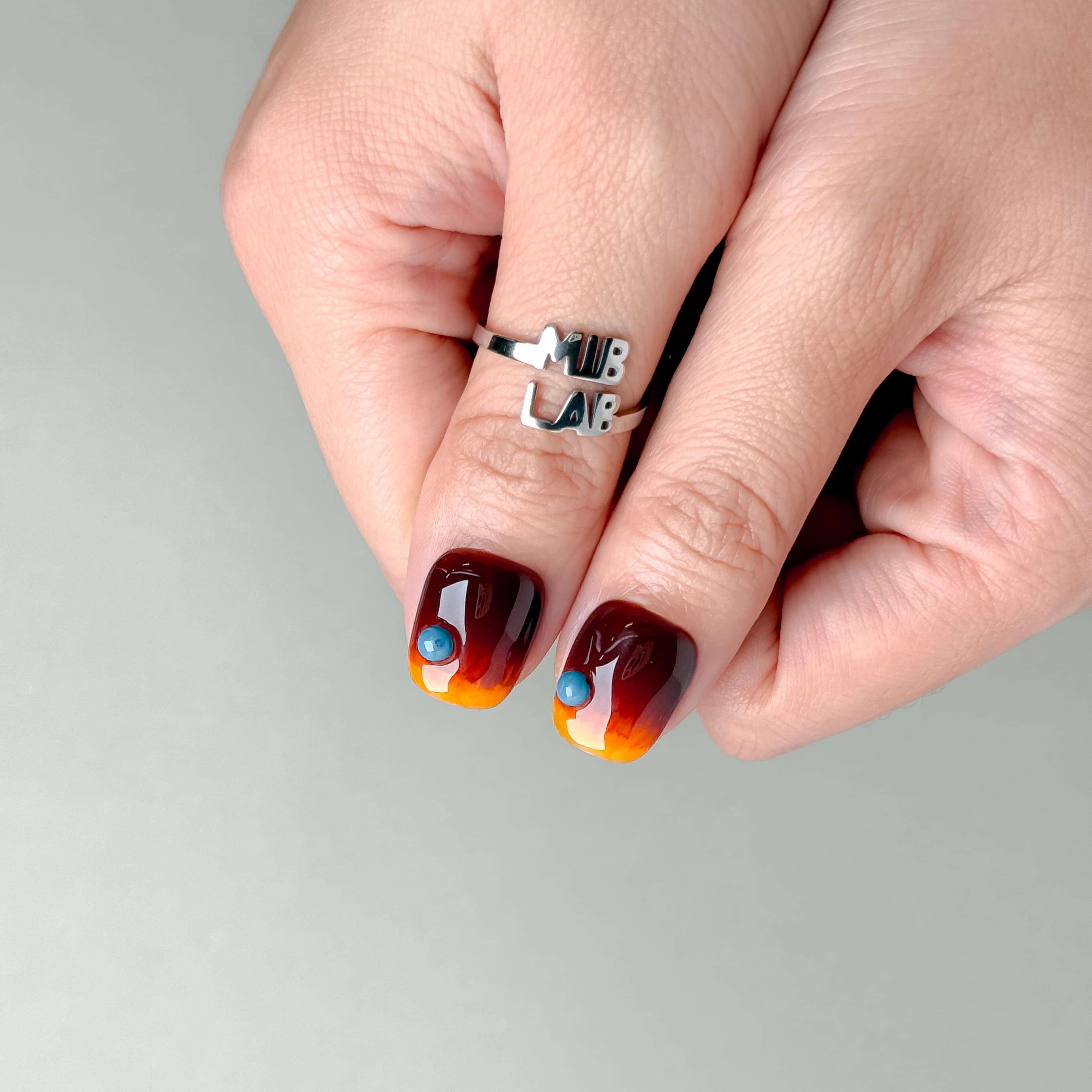 Deux mains avec How it’s Done : press on nails premium ambre-noir, style soirée, manucure rapide sans salon, Genève.