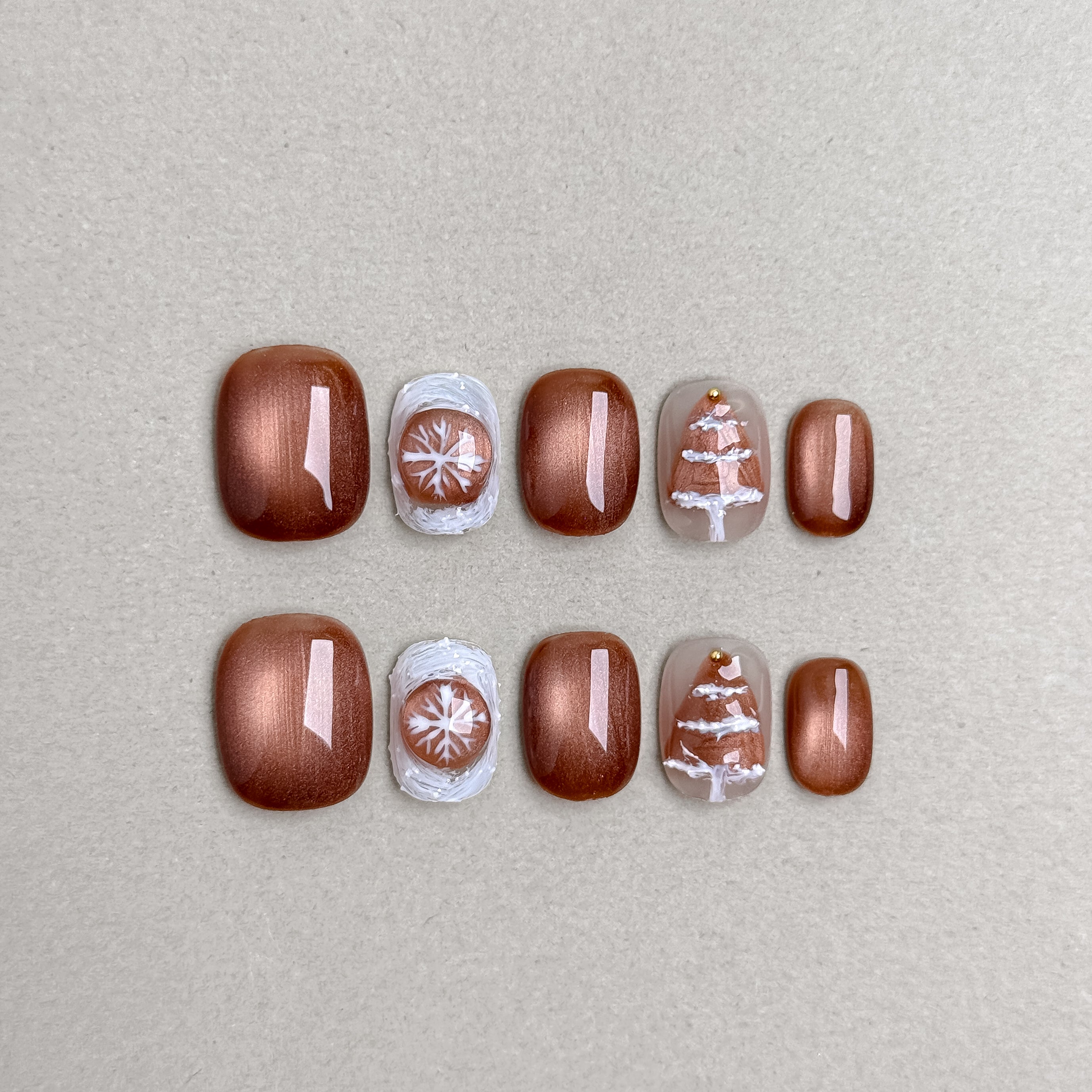 Set of reusable press-on nails in bronze brown and nude tones with white snowflake accents, MIBLAB Snow Me collection Geneva.