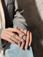 Manucure XO portée : press on nails blanc à cœurs noirs, look doux et chic, ongles sans gel, Genève.