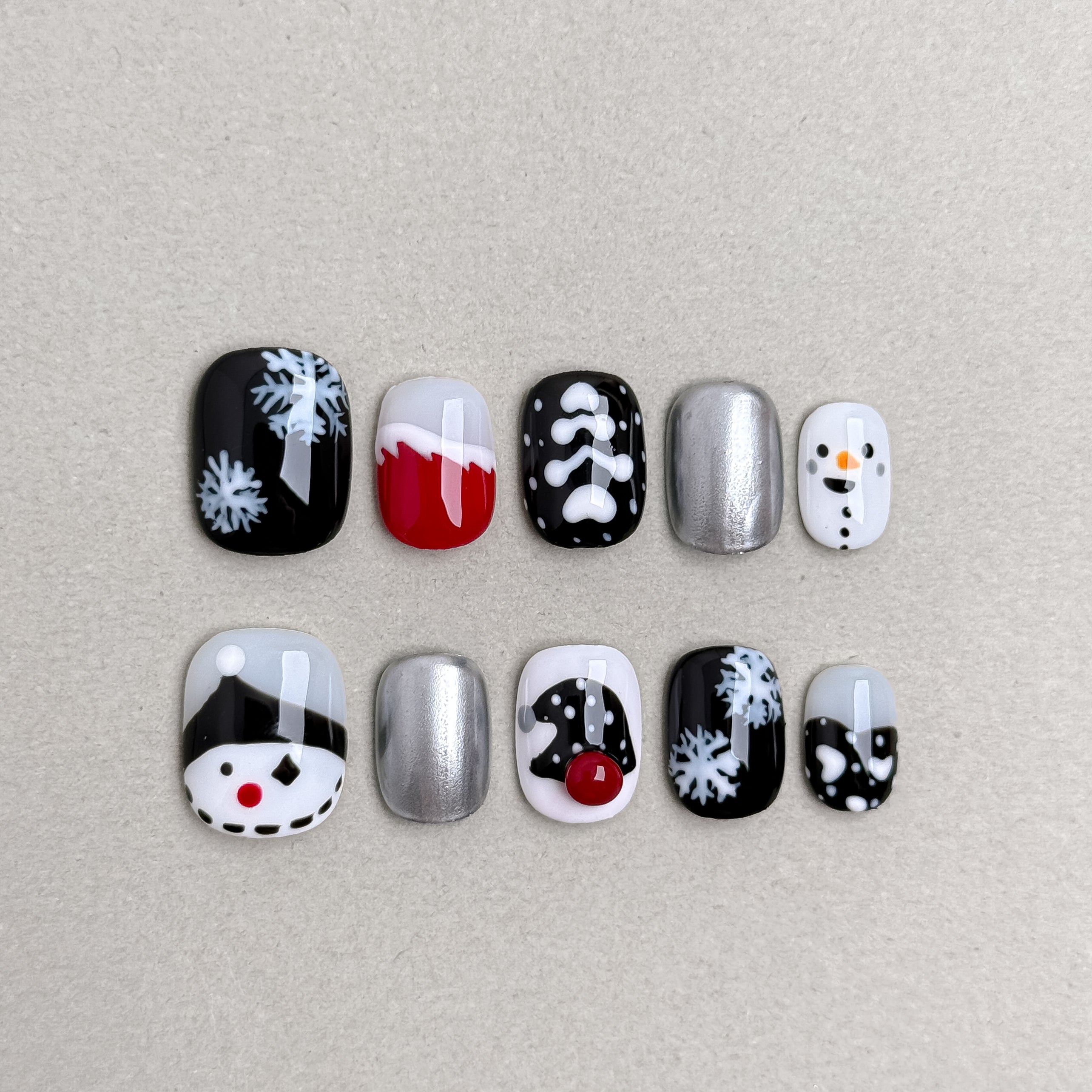 Set of reusable press-on nails in black, silver, and red with snowflake and snowman designs, MIBLAB Inkmas collection Geneva.