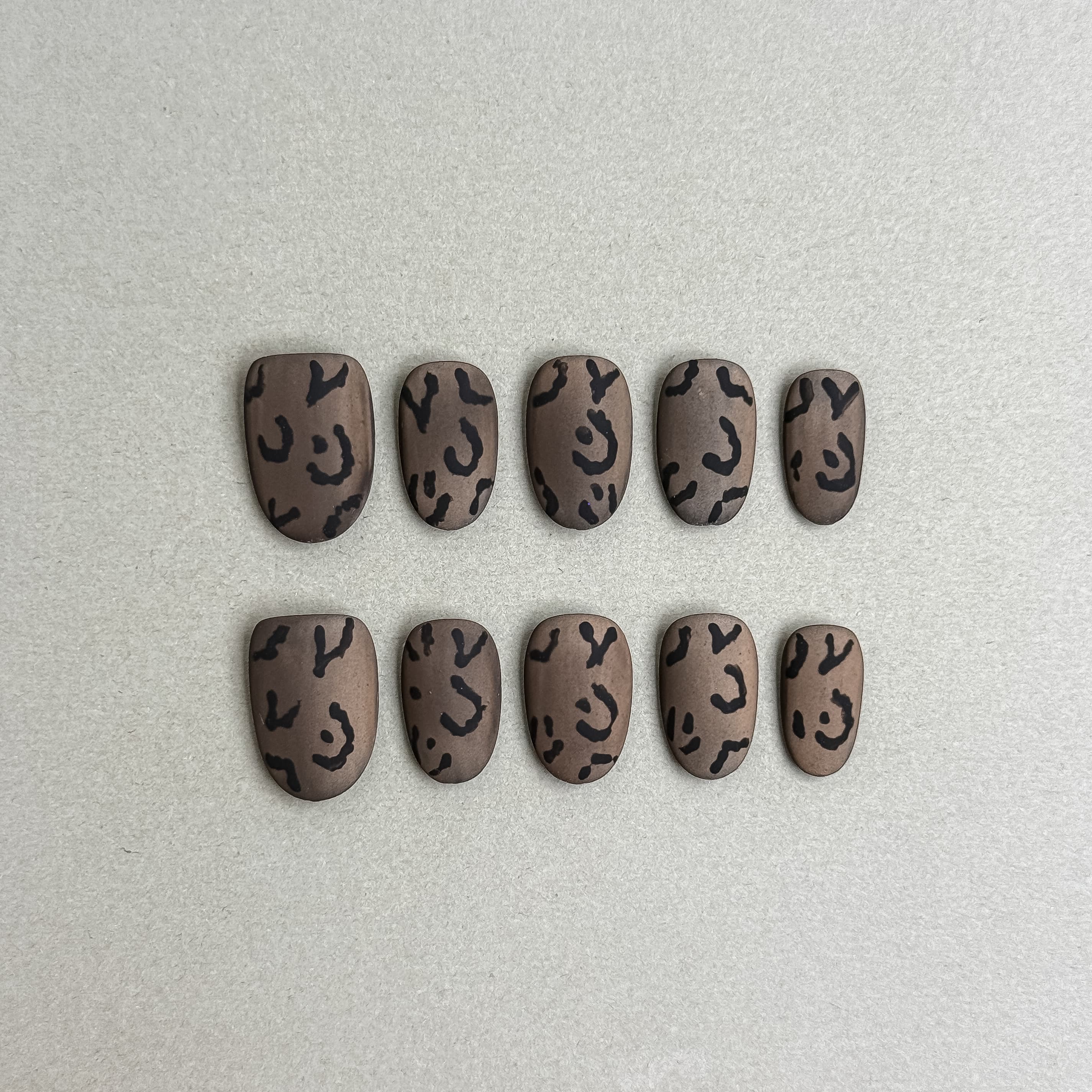 Nyx : faux ongles réutilisables nude taupe avec motifs noirs abstraits, press on nails premium, finition brillante.