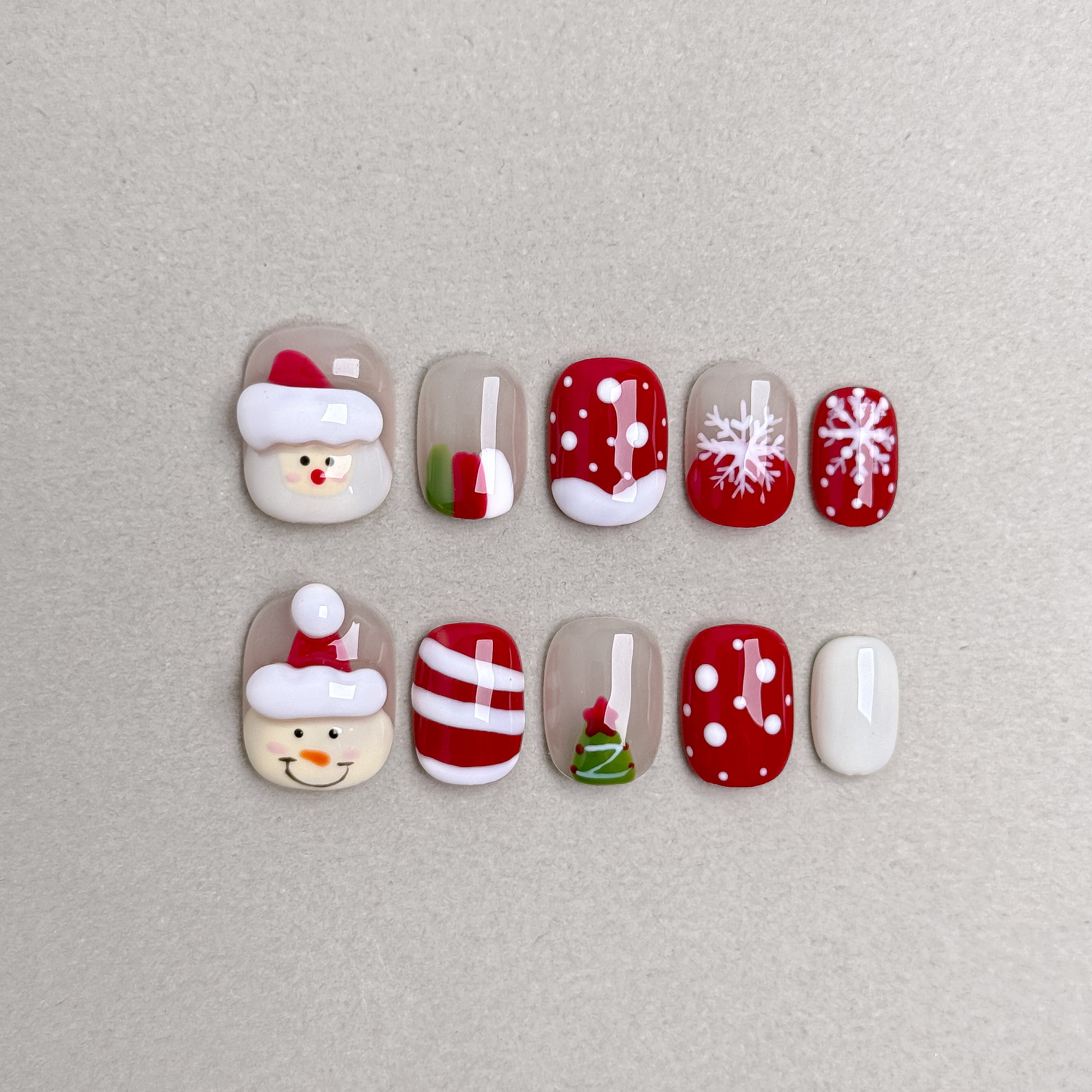 Set of reusable press-on nails with Santa Claus, candy cane, and snowflake designs in red, white, and green, MIBLAB Santa Tell Me collection Geneva.
