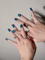 Détail Hors Mer sur mains : faux ongles premium réutilisables bleu laqué, style soirée, tenue longue durée, Suisse.