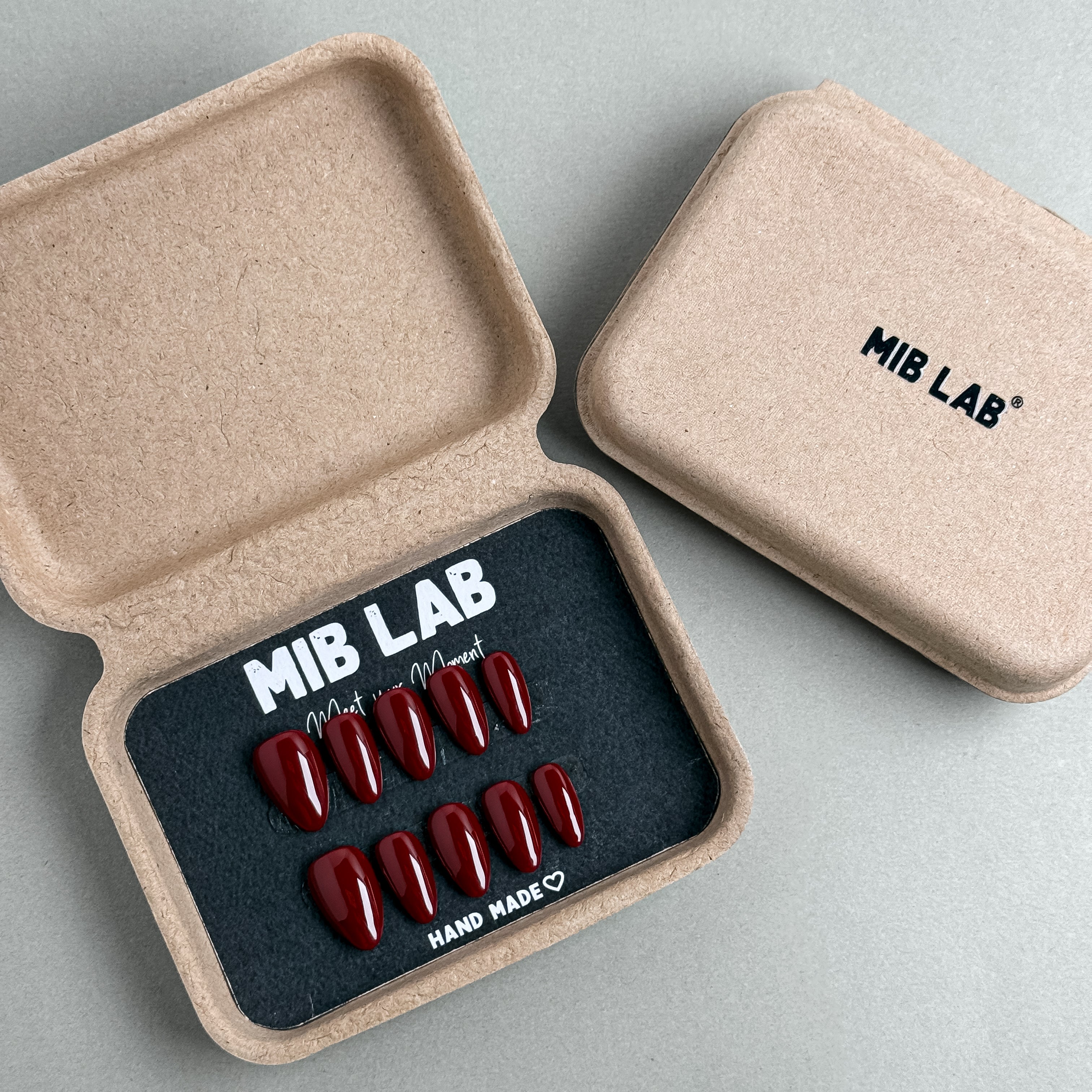 MIBLAB Wine Not Almond press-on nail set in dark burgundy red tone, packaged for boutique display in Geneva.